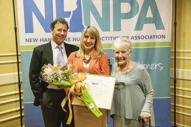Christine Ferreri 2019 NP of the Year, stands with her award and flowers between her husband and mother. 